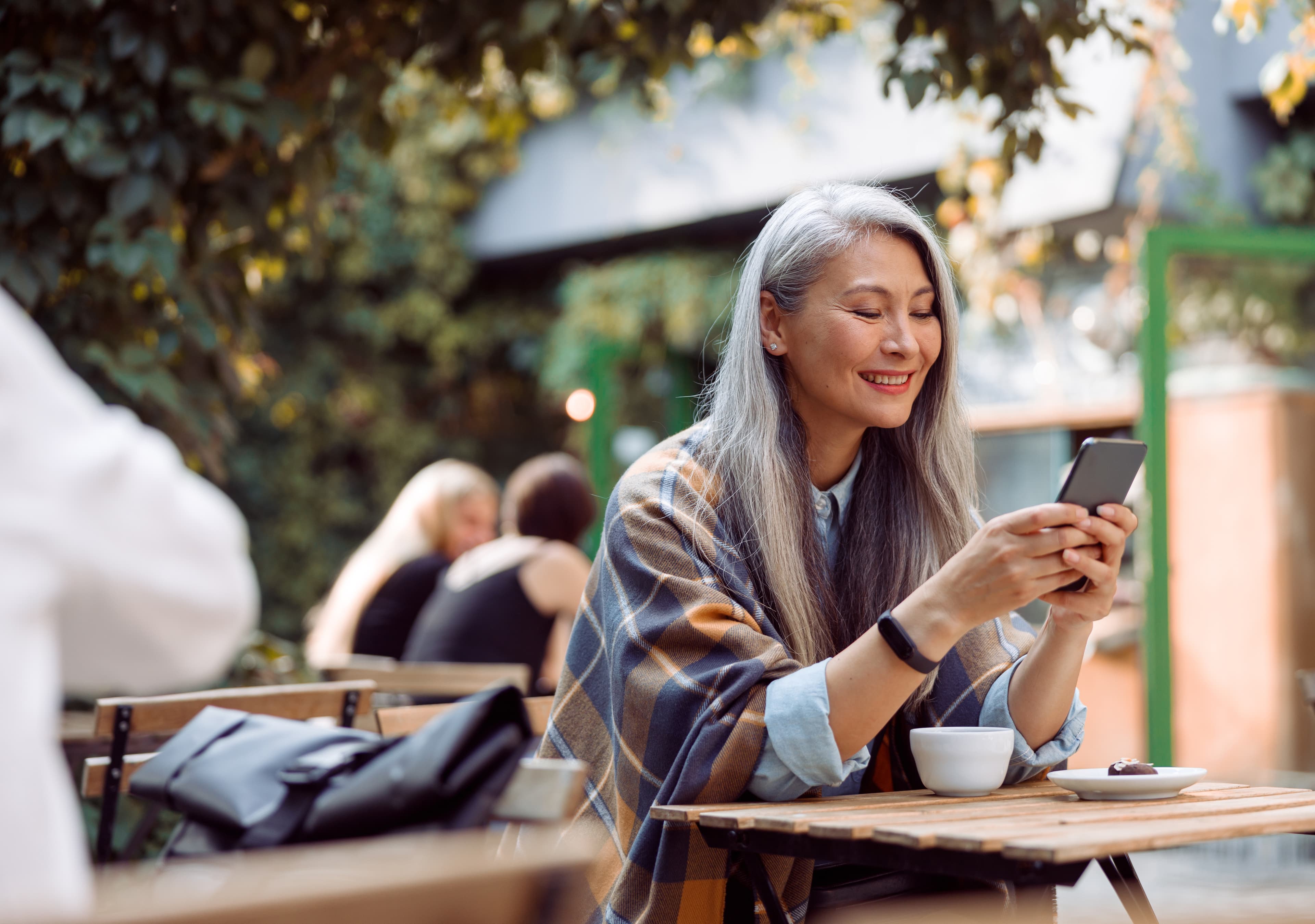 A woman is sitting in a café and reading something on her phone.