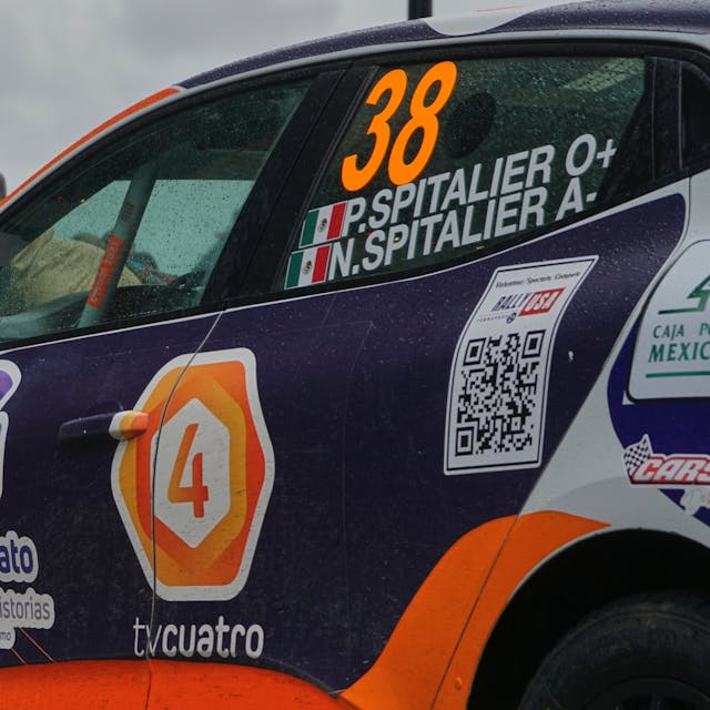Racing car with QR code on the side. Cloudy weather. People in the background.
