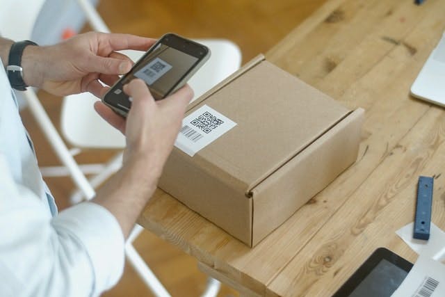 A person is scanning a package with a QR code sticker.
